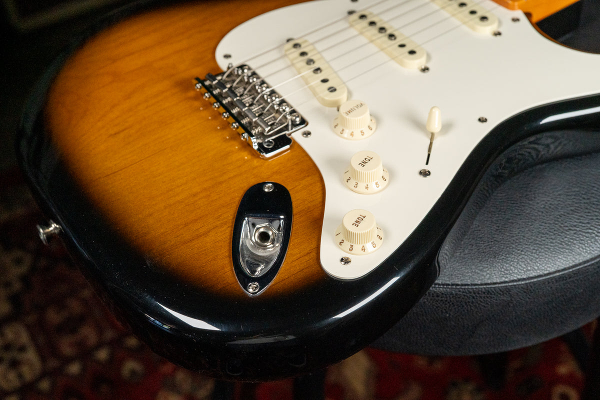 Close-up of the guitar's lower body, showing the 2-tone sunburst finish, white pickguard, chrome bridge, and cream control knobs.