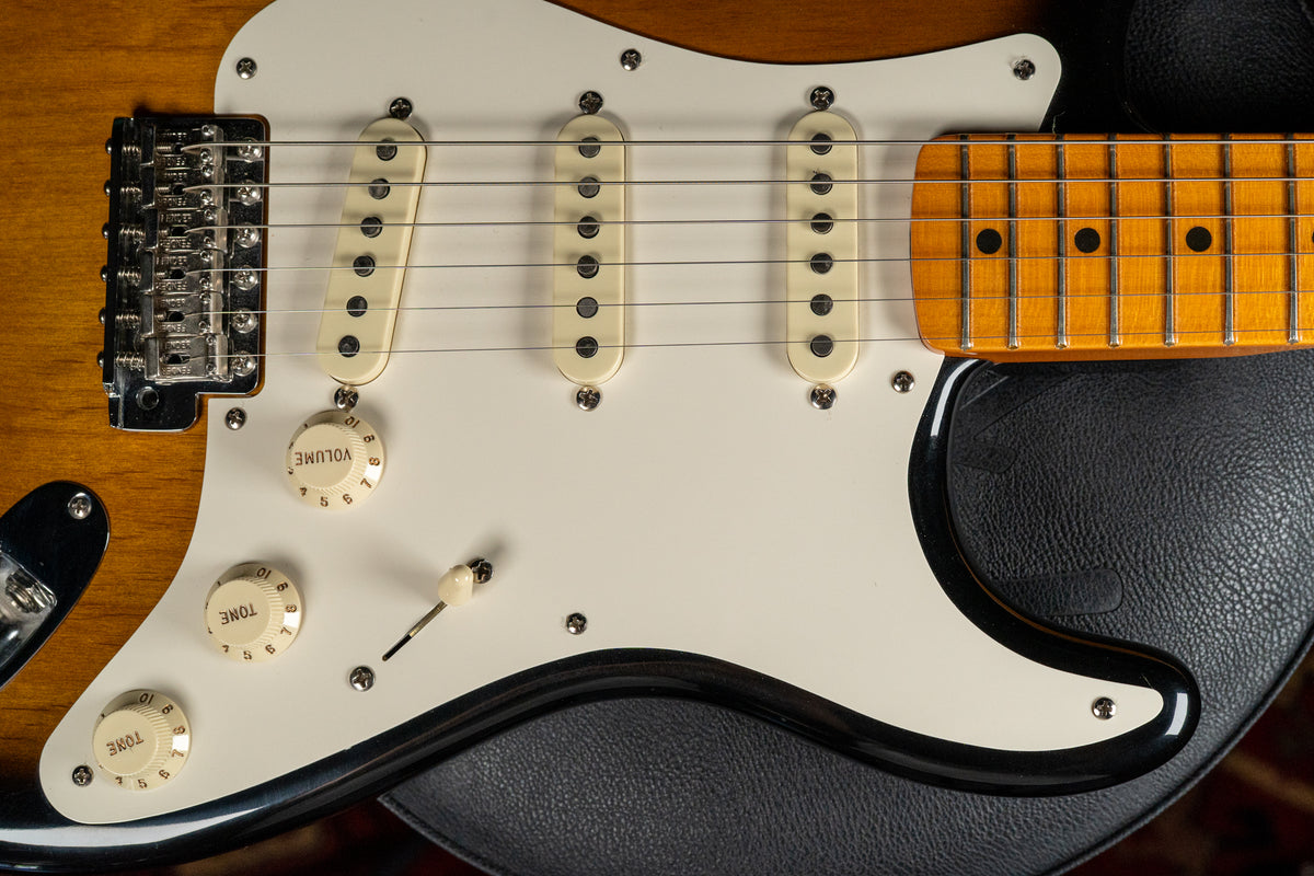Close-up of the guitar's body, showing the sunburst finish, white pickguard, three cream single-coil pickups, and chrome tremolo bridge.