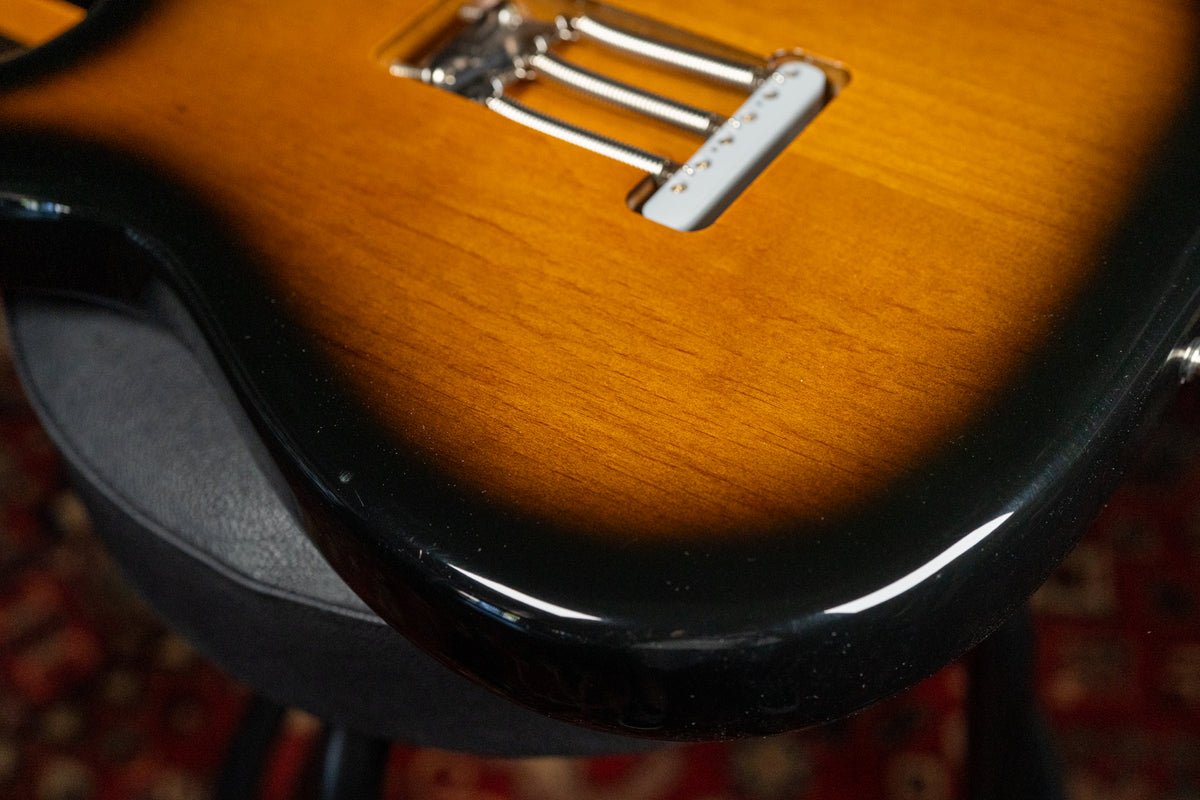 Close-up of the guitar's lower bout, showing the sunburst finish, chrome tremolo bridge, and a small ding on the black edge.
