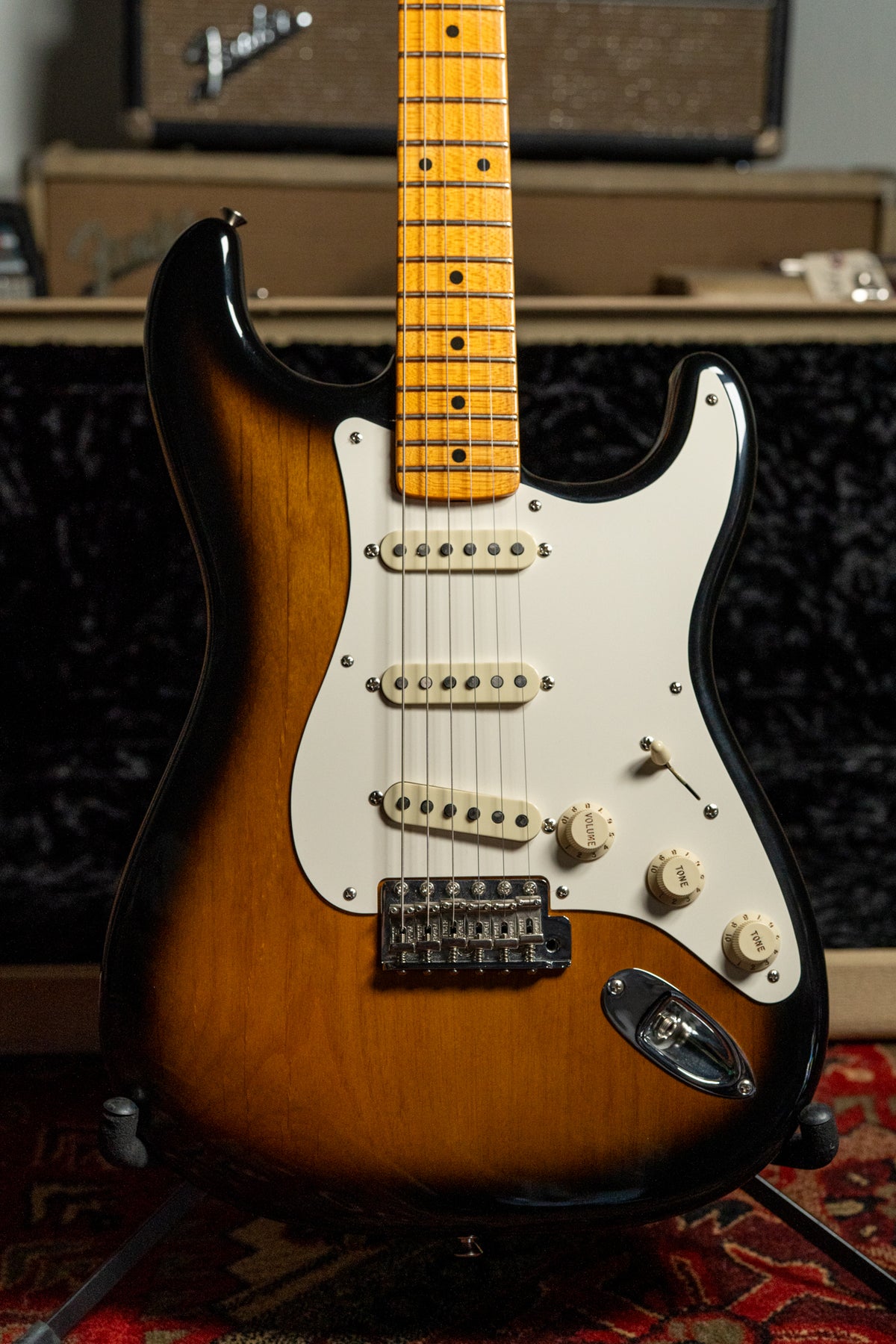 Full-frame, front-facing view of a two-tone sunburst electric guitar with a white pickguard, three single-coil pickups, and a maple neck.
