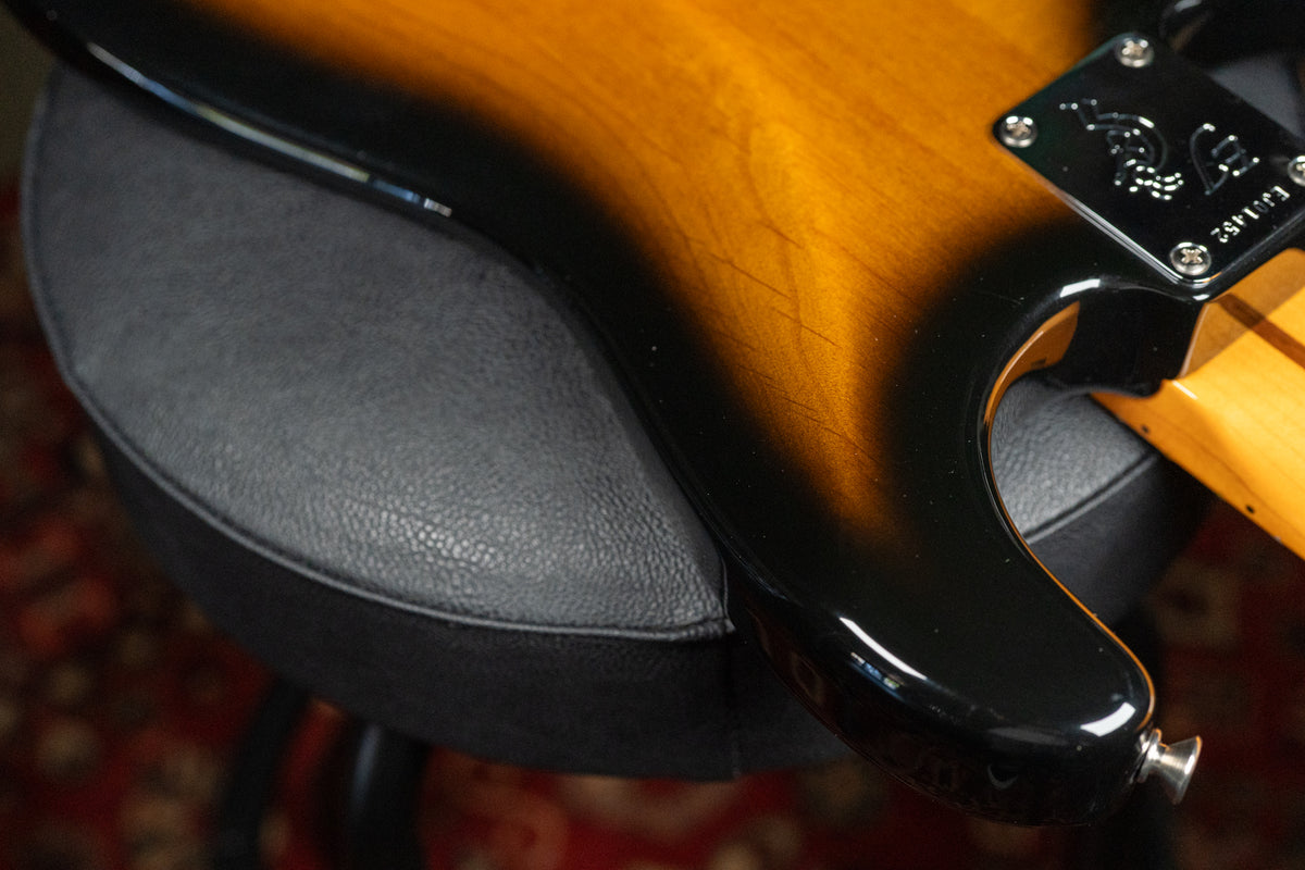 Close-up of the lower bout and neck joint, showing the sunburst finish with light checking and a chrome strap button.