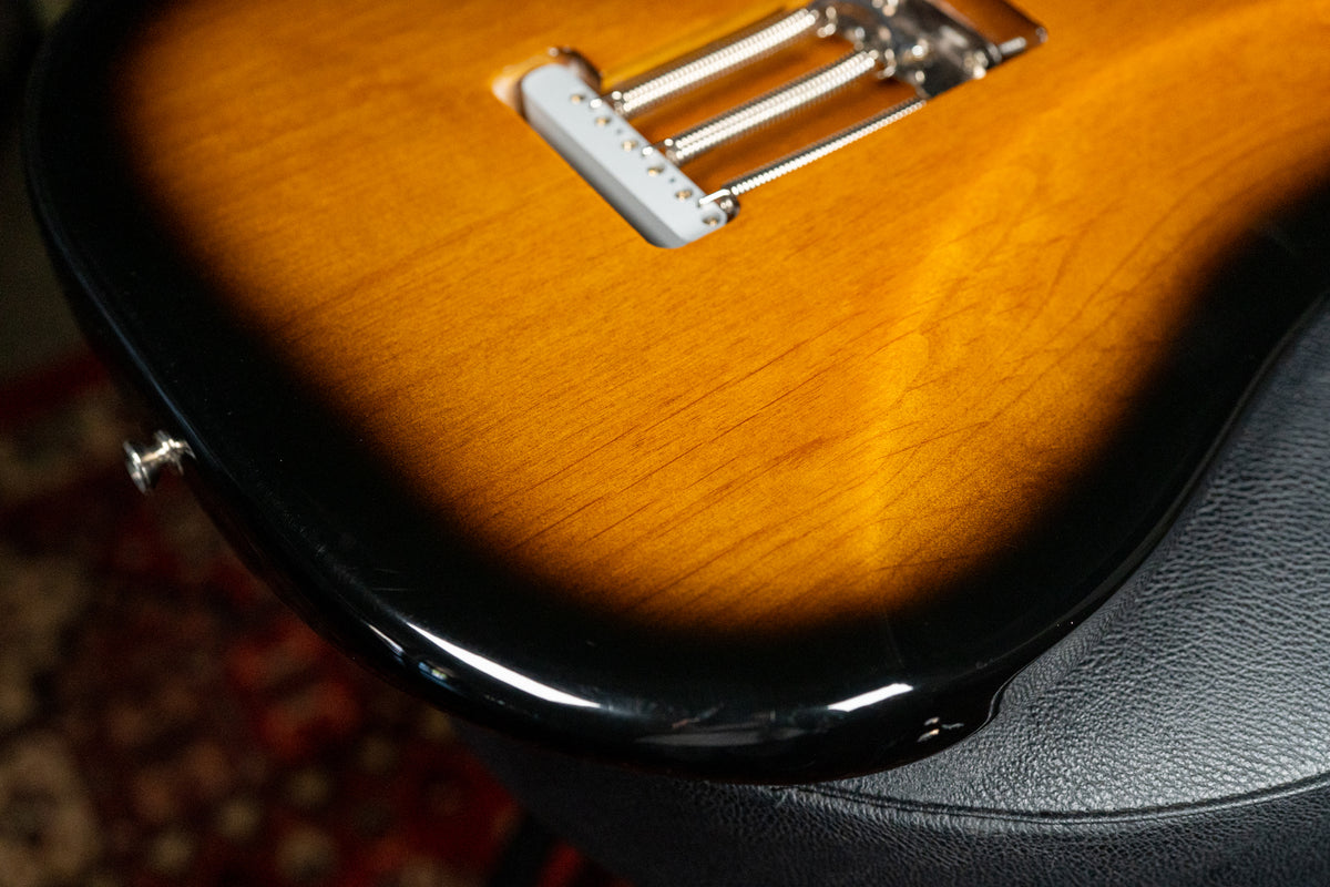 Close-up of the guitar's lower body, showing the sunburst finish, tremolo bridge with springs, and minor scratches on the black edge.