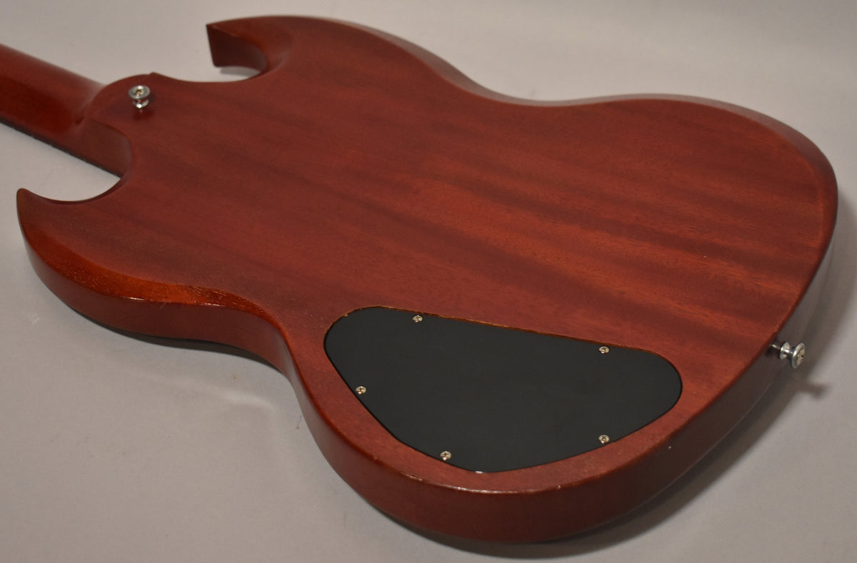 The back of a faded worn cherry SG, showing the neck joint, black control cavity cover, and strap buttons.