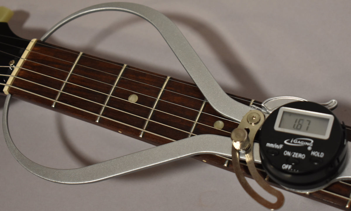 A digital fret height gauge shows a reading of 1.87mm on the dark rosewood fretboard with dot inlays.