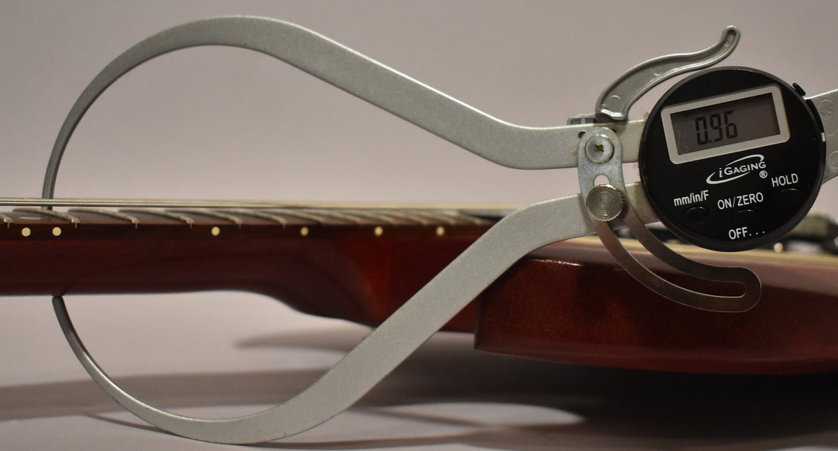 A close-up of the guitar's worn cherry neck and fretboard, with a digital caliper measuring the string height at 0.96mm.