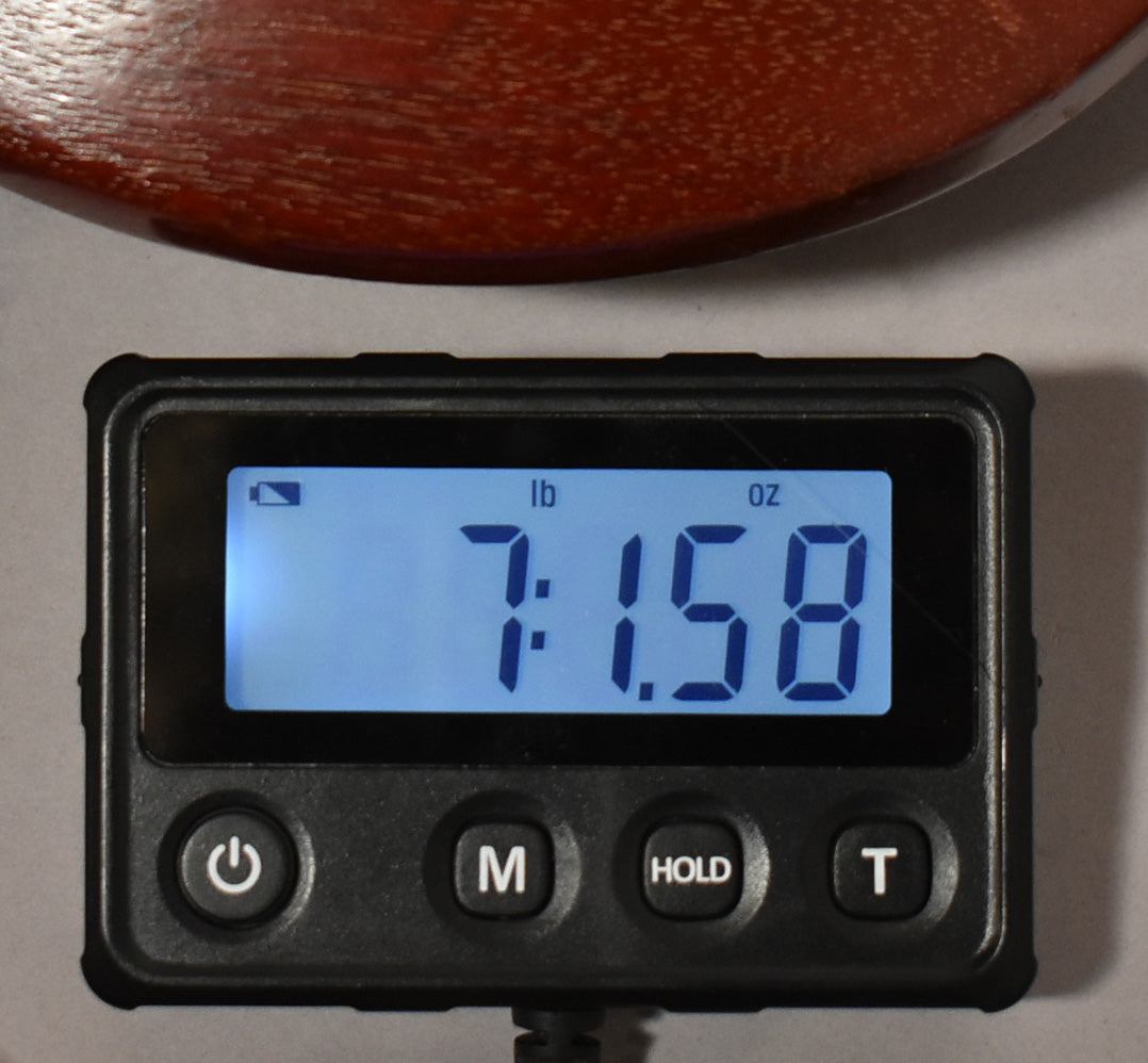 A digital scale displays "7:1.58" in blue, indicating 7 pounds, 1.58 ounces, with a worn cherry guitar body above.