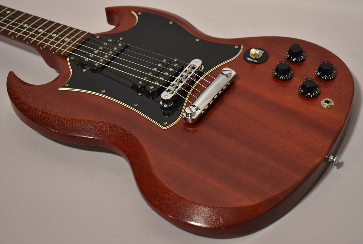 Cherry red SG body with a worn, faded finish, black pickguard, two humbuckers, chrome tune-o-matic bridge, and four black control knobs.