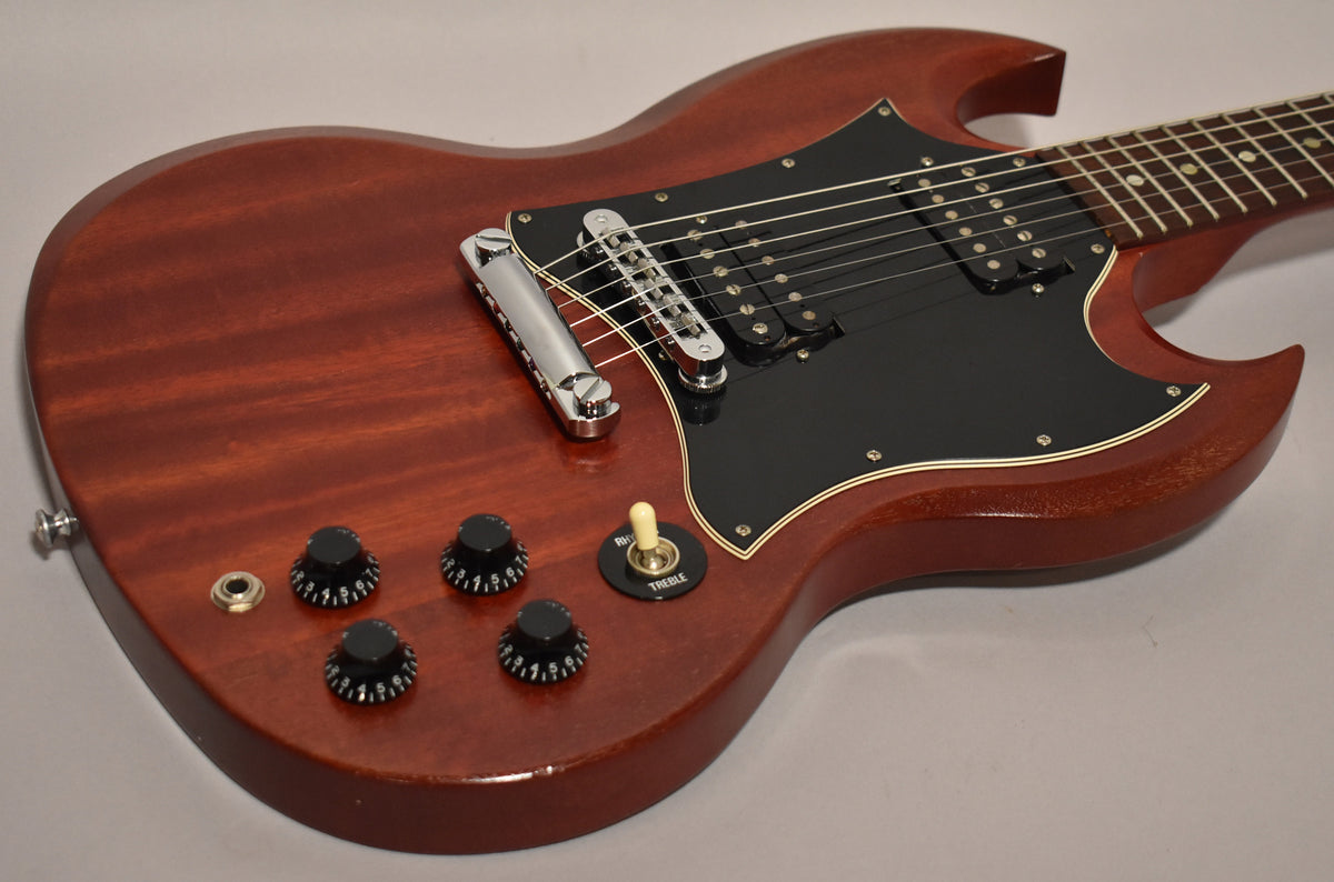 Cherry red SG body with a faded, worn finish, black pickguard, chrome hardware, and four black control knobs.