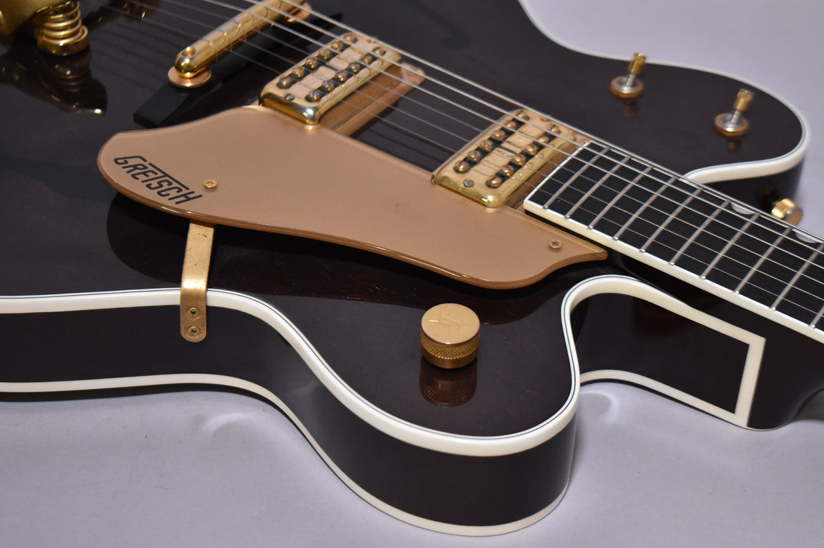 Close-up of the dark walnut body with cream binding, gold hardware, two humbuckers, and a single knurled gold control knob.