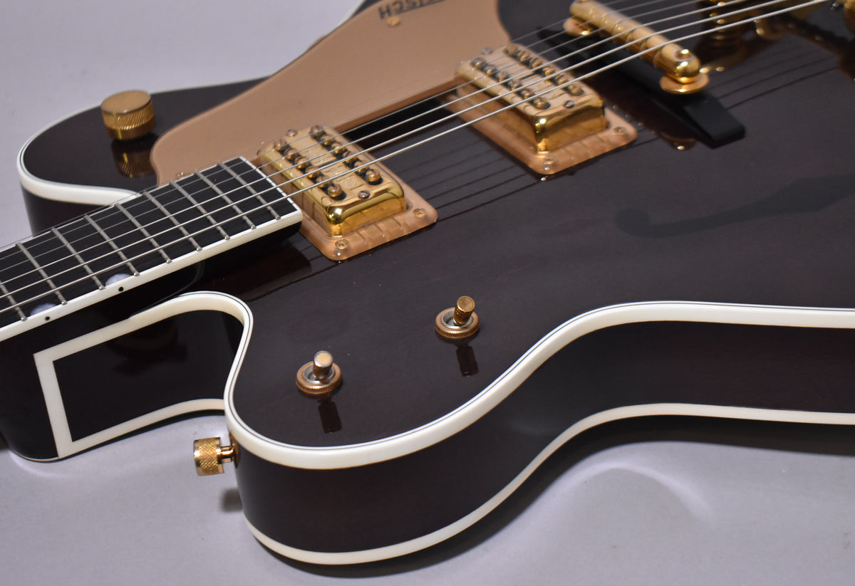 Close-up of the dark walnut body with cream binding, gold hardware, two pickups, and three gold-knobbed controls.