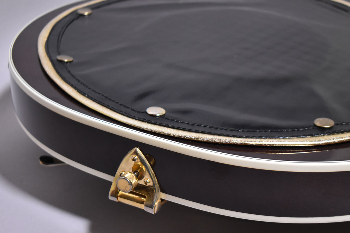 Close-up of the guitar's dark walnut body with white binding, showing a black leather pad with gold trim and a gold strap button.