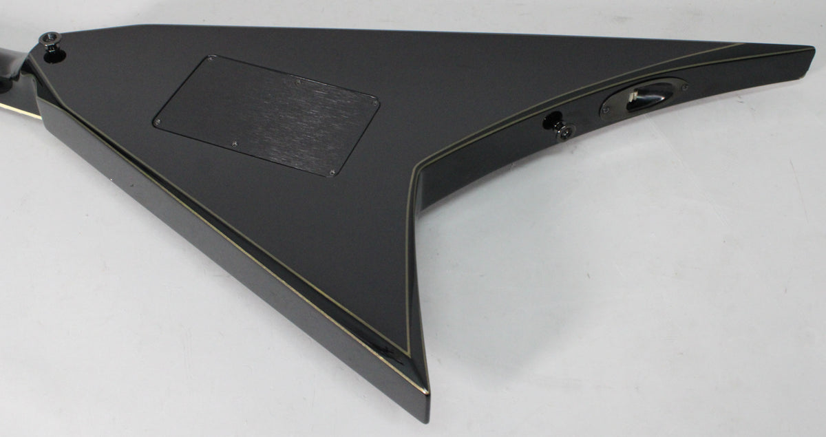 The guitar's matte black V-shaped body, with gold pinstripes, is angled to show the rear control cavity and output jack.