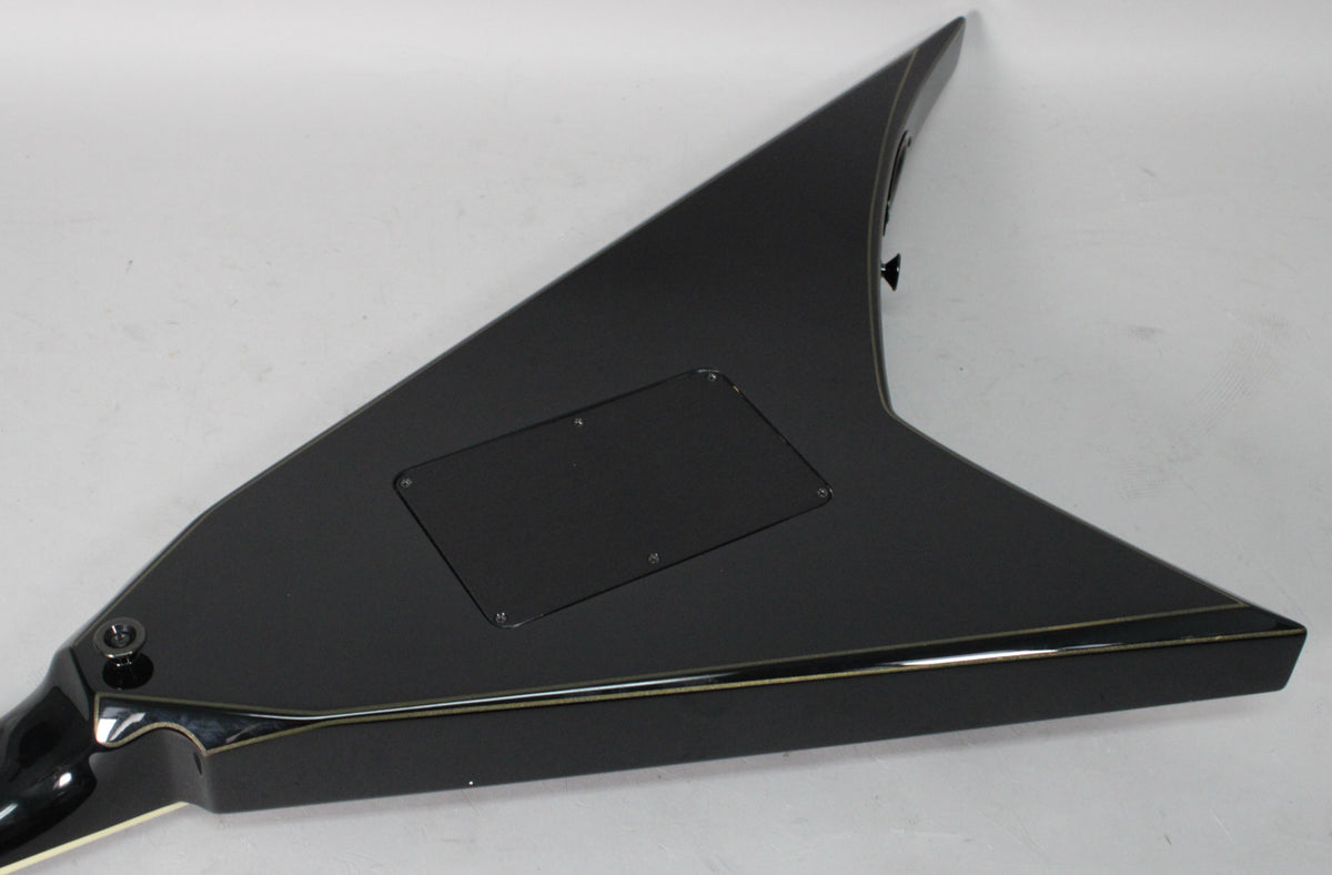 The back of a black V-shaped guitar body, with a rectangular control cavity cover and gold pinstripes along the edges.