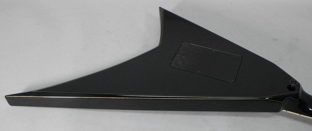 The back of a black V-shaped guitar with gold pinstriping, showing a rectangular control cavity cover and some light scuffing.
