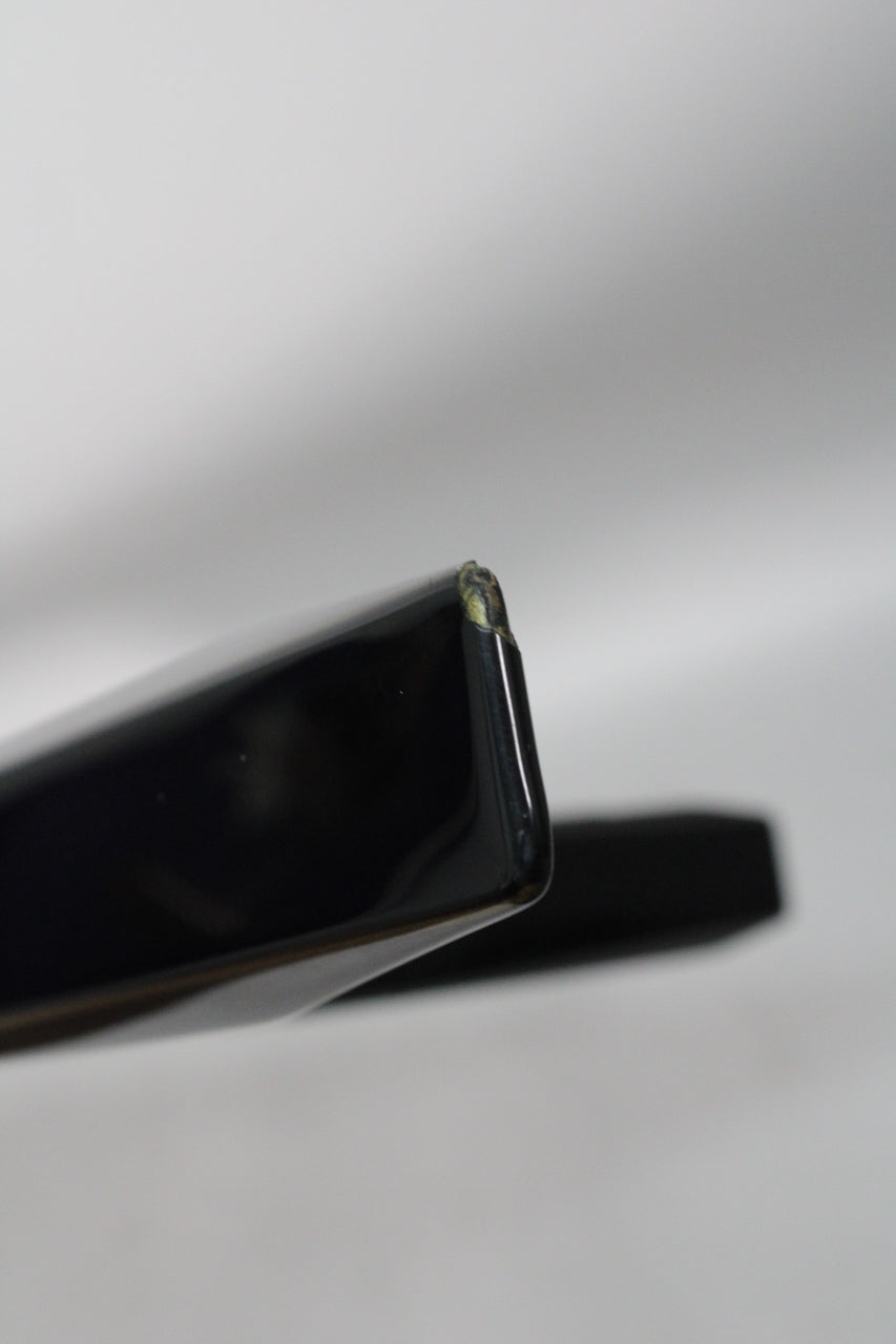 Close-up of the black guitar's V-shaped body wing tip, showing a chip in the finish revealing lighter wood underneath.