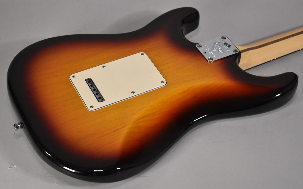 The sunburst Stratocaster's back shows a cream tremolo cover, chrome neck plate, and a light-colored neck extending from the body.