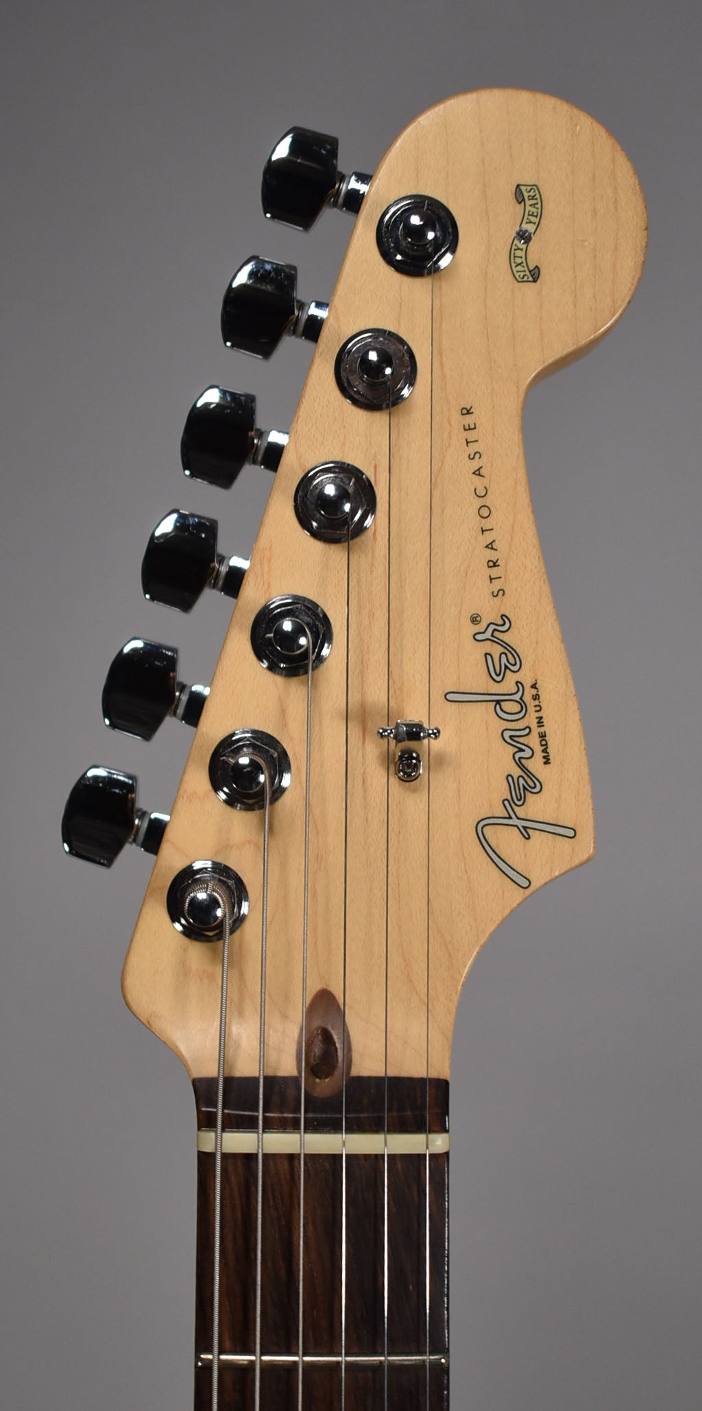 Close-up of the maple headstock and dark rosewood fretboard, showing six chrome tuners, a string tree, and a "Sixty Years" banner.