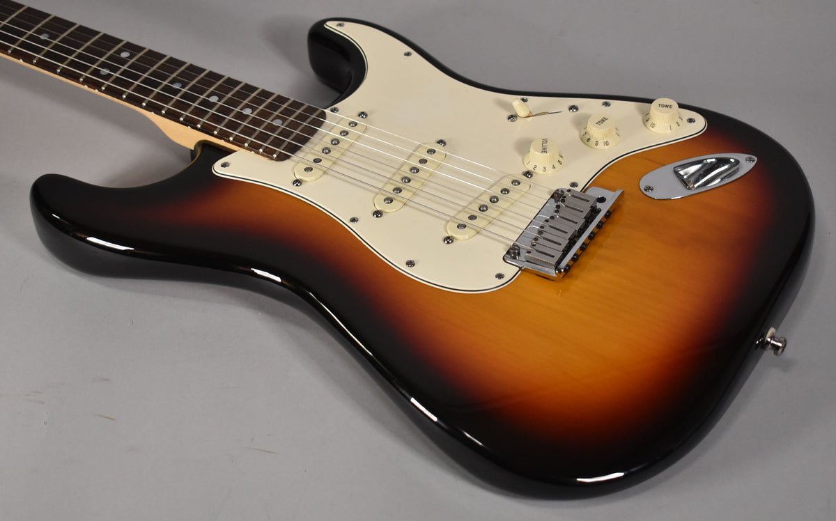 The sunburst Stratocaster body, with its cream pickguard and controls, is angled to show the lower bout and part of the fretboard.