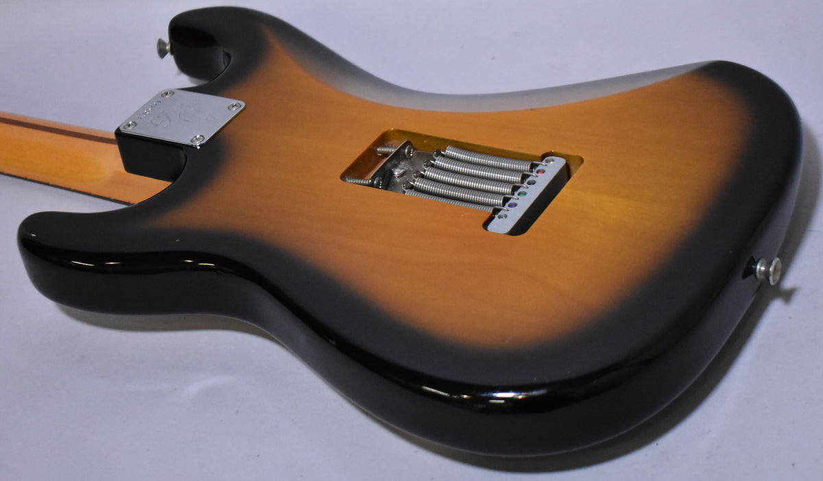 The guitar's sunburst body, viewed from the back, shows a chrome neck plate and a tremolo spring cavity with five springs.