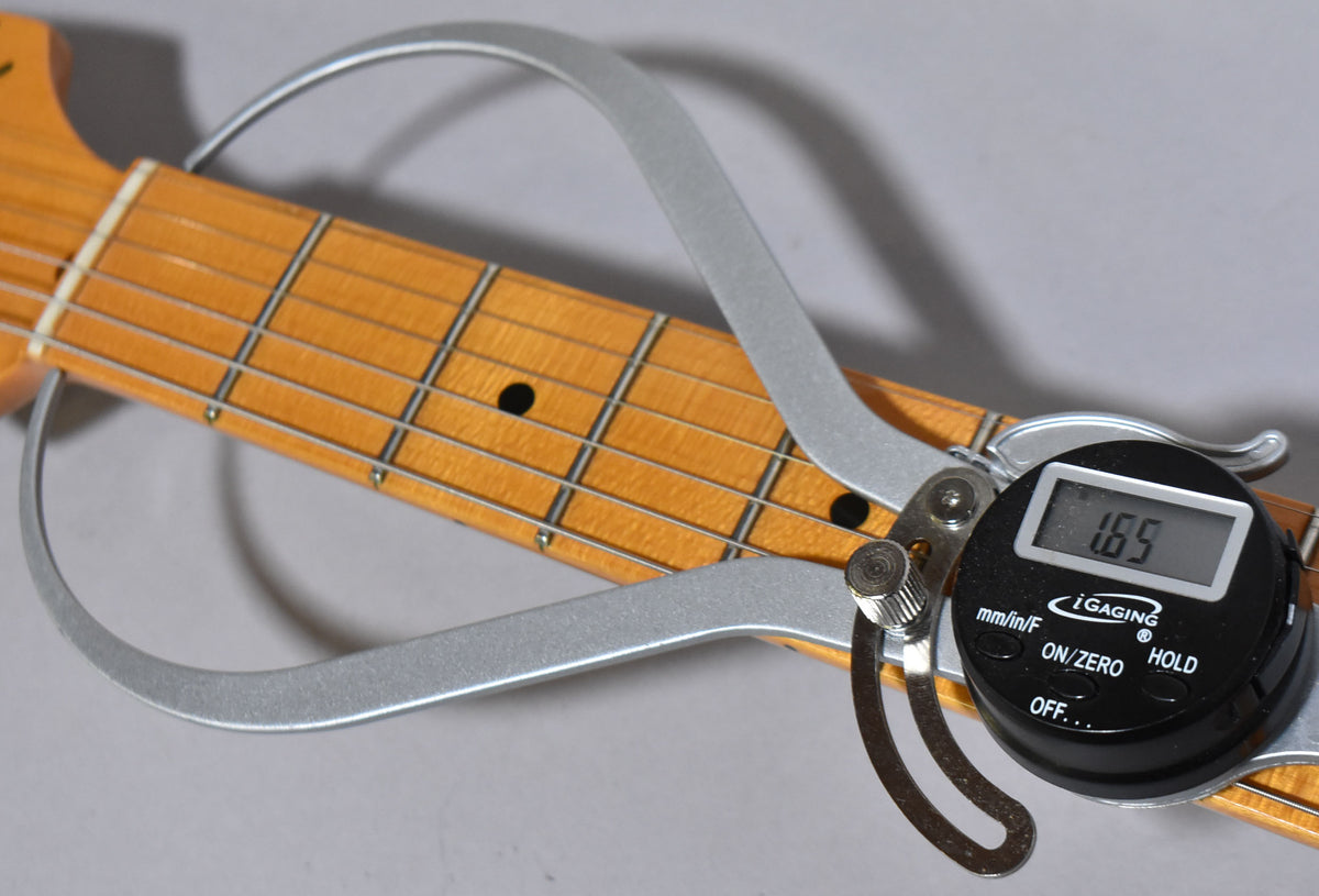 A digital fret height gauge shows 1.65mm on the maple fretboard with black dot inlays and light wear.