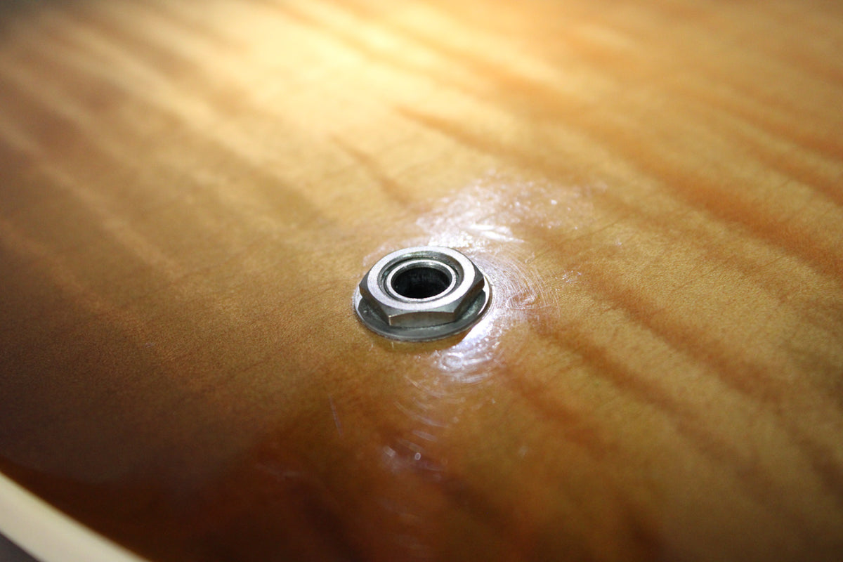 Close-up of the guitar's figured sunburst body, showing the chrome output jack with light wear and minor finish swirling around it.