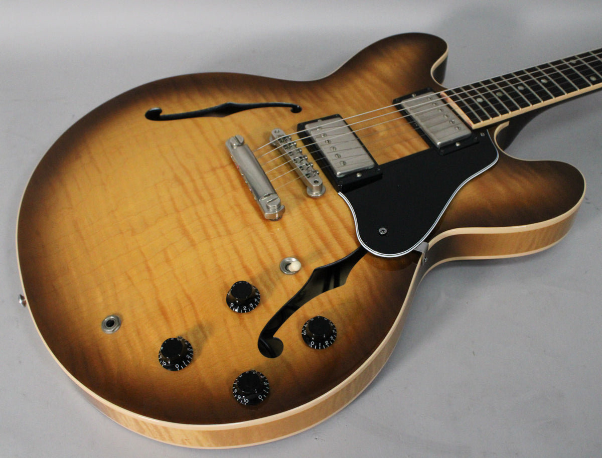 The figured sunburst semi-hollow guitar body, with f-holes, chrome hardware, black pickguard, and four black control knobs.