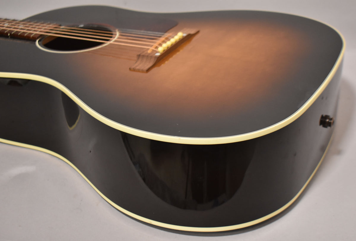 The lower bout of a sunburst acoustic guitar, showing the bridge, soundhole, and endpin jack.