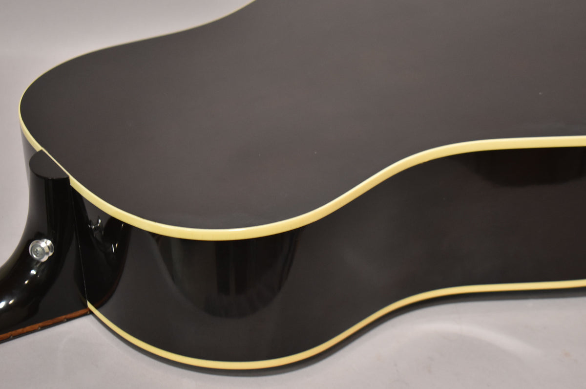 Close-up of the guitar's lower bout and waist, showing the dark sunburst finish, cream binding, and a strap button on the neck heel.