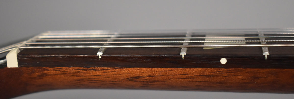 Close-up of the guitar's dark brown fretboard and walnut-stained neck, showing the nut, frets, and side dot markers.