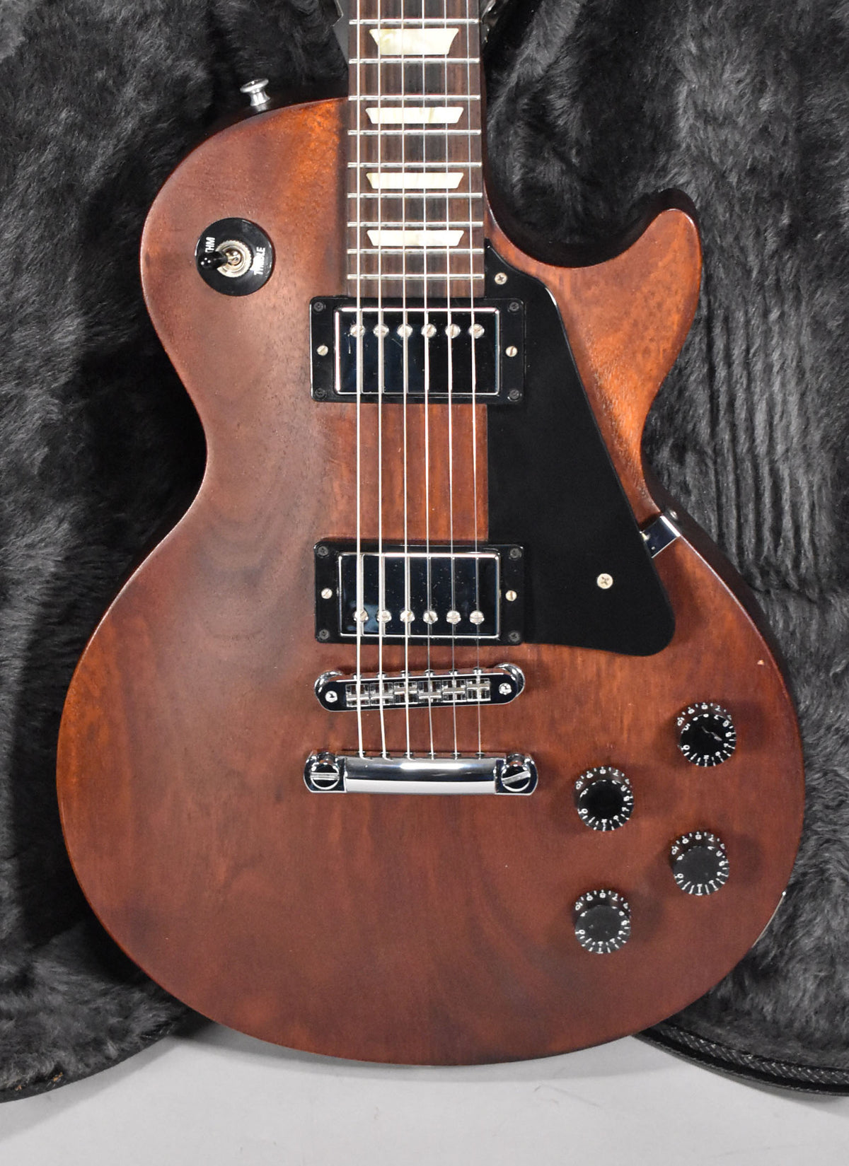 Full-frame view of a faded walnut Les Paul, showing its matte finish, black pickguard, chrome hardware, and four black knobs.