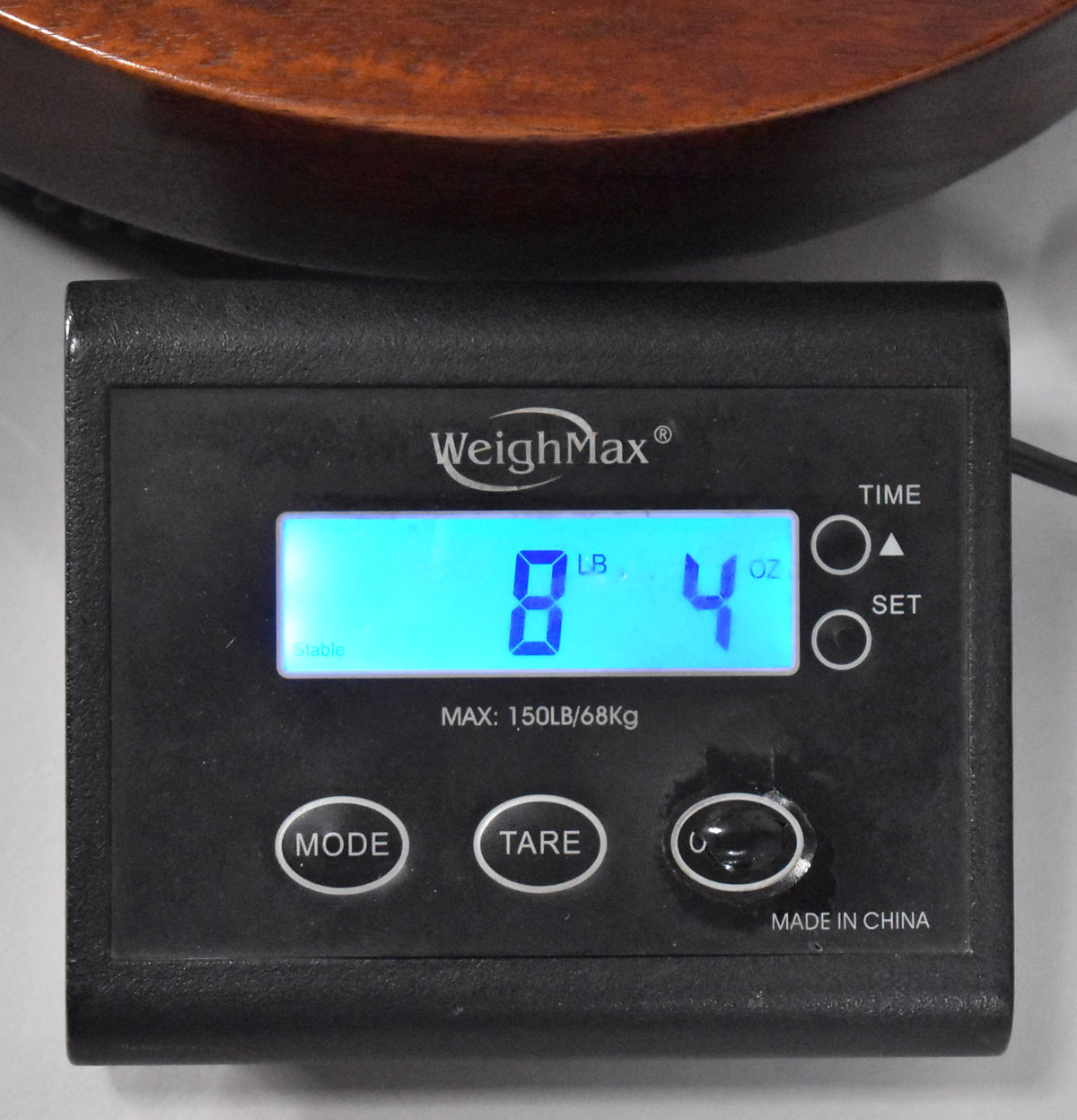 The faded walnut body of the guitar rests on a black digital scale displaying "8 LB 4 OZ" in blue.