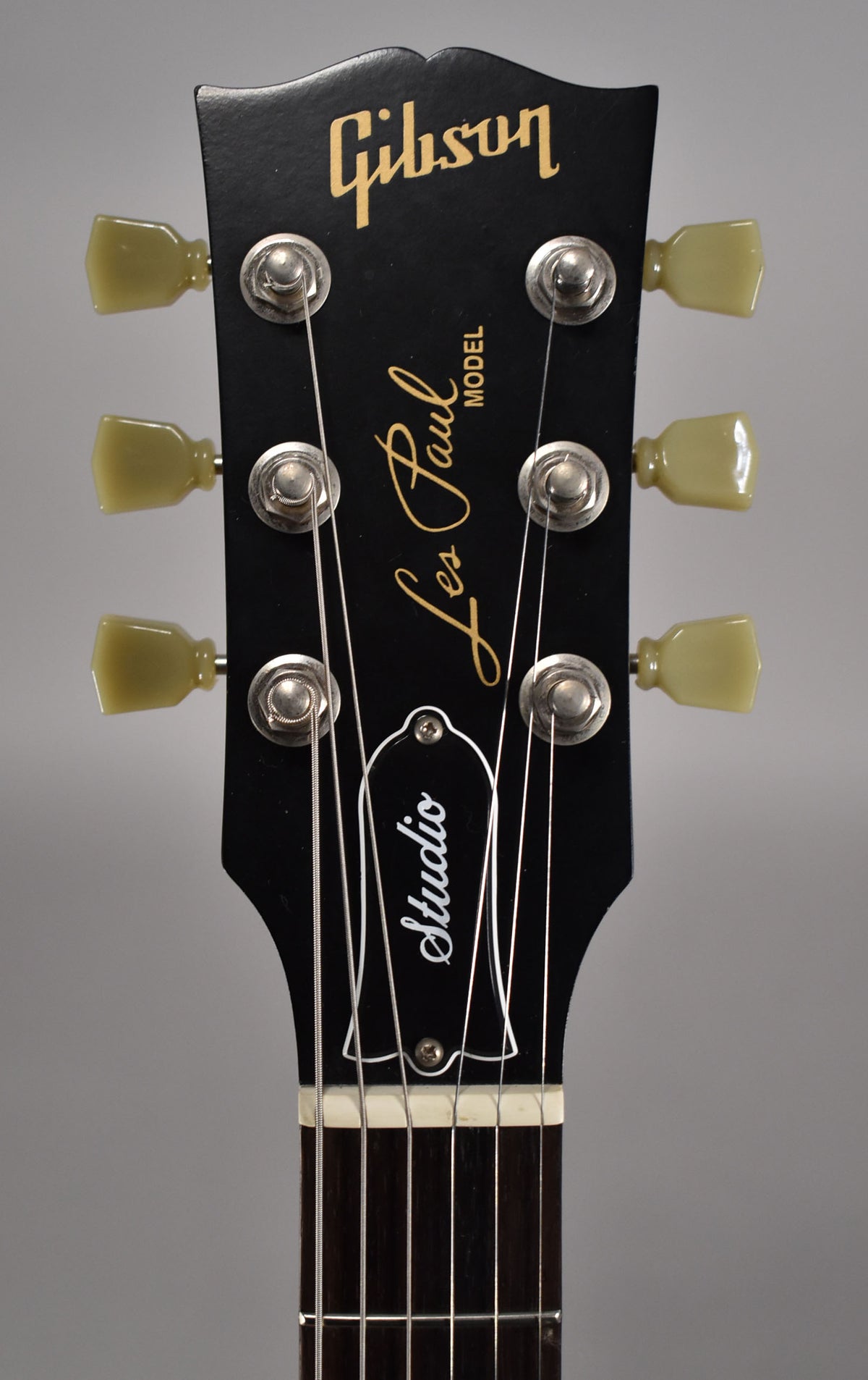 Close-up of the black headstock with cream tuners, showing light wear on the tuning pegs and a few minor scratches.