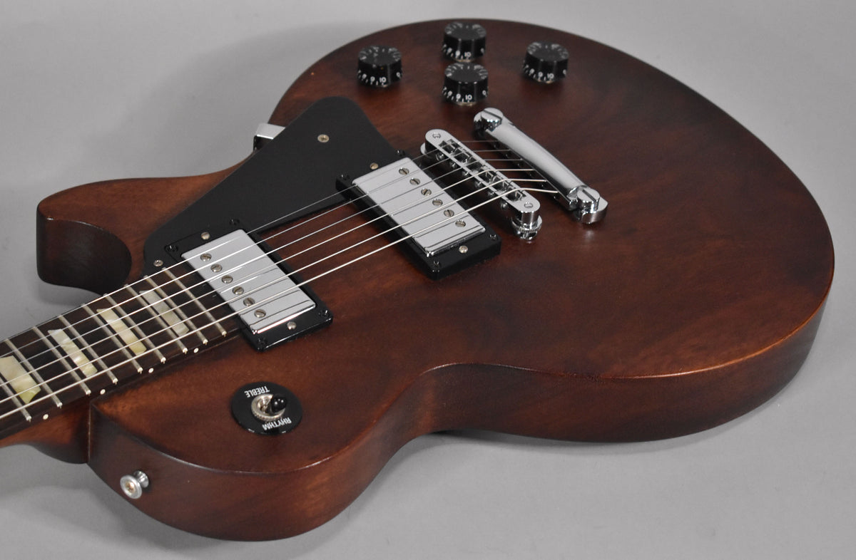 Close-up of a faded walnut electric guitar, showing the body, chrome hardware, black pickguard, and four black control knobs.