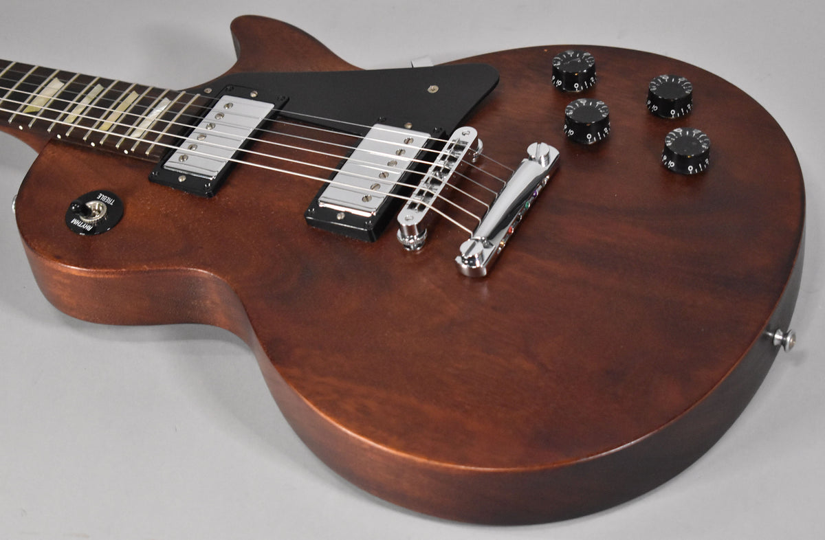 Close-up of a faded walnut Les Paul body, showing the chrome bridge, tailpiece, two humbuckers, black pickguard, and four black control knobs.