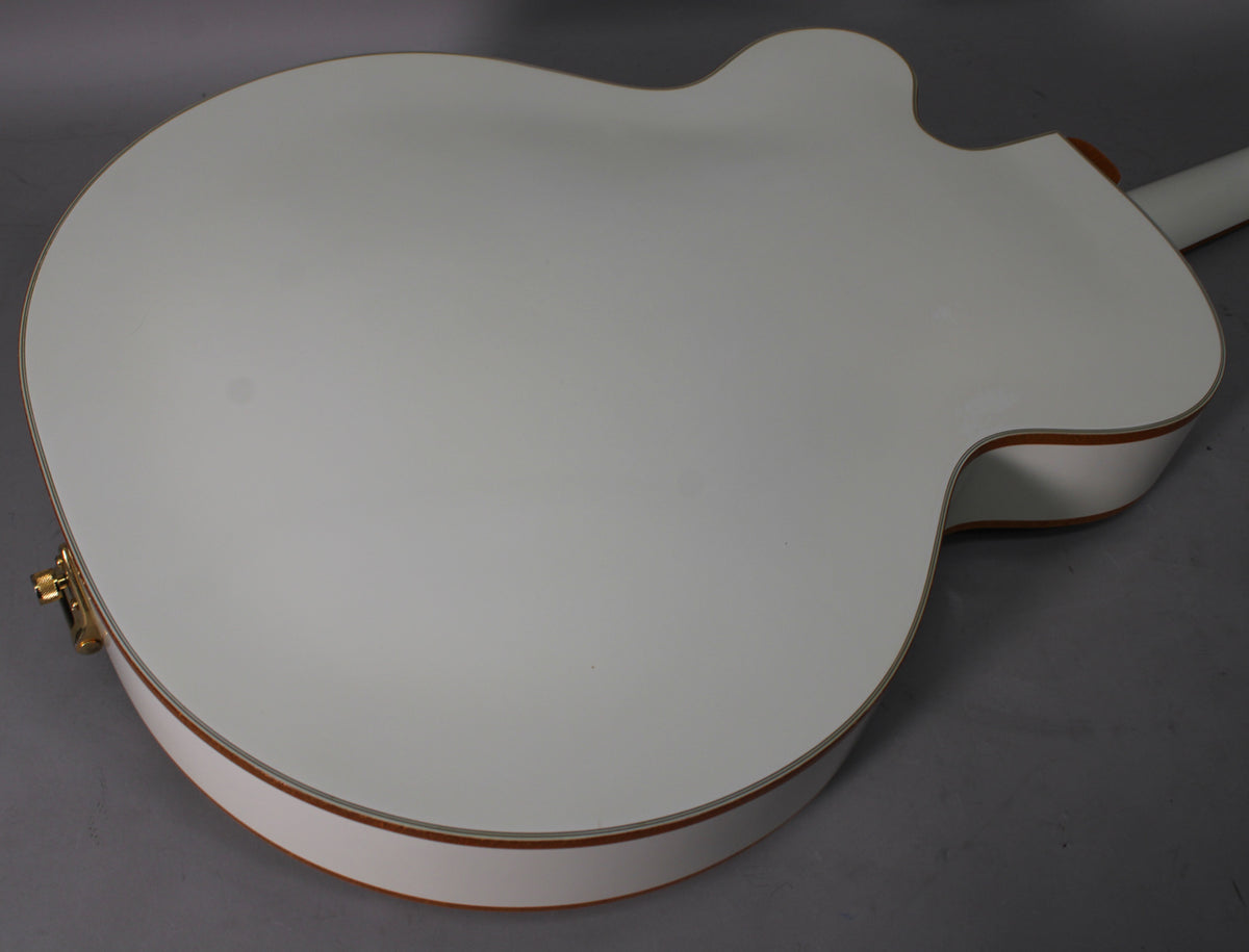 The back of a white hollow-body electric guitar, showing the body's binding and a gold strap button on the lower bout.