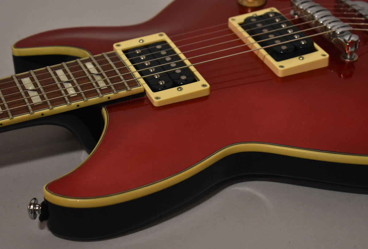 Close-up of the guitar's upper body, showing the candy apple red finish, cream binding, two humbuckers, and part of the fretboard.