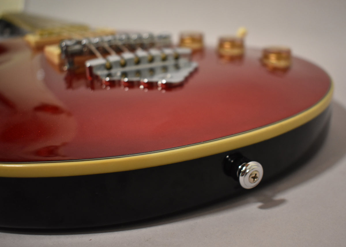 Close-up of the guitar's lower bout, showing the Candy Apple Red top, cream binding, black sides, and chrome output jack.
