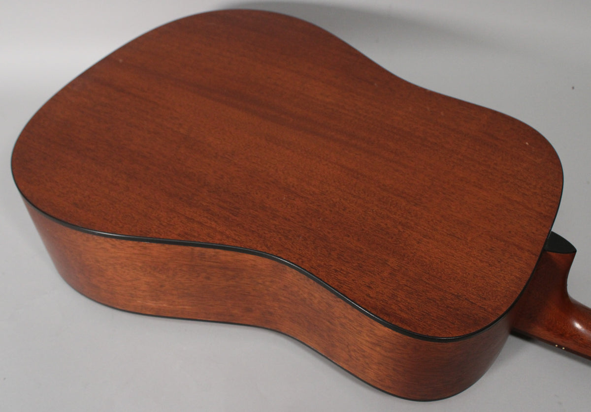 The guitar's back and side are visible from above, showing a reddish-brown satin finish with black binding and light wear.