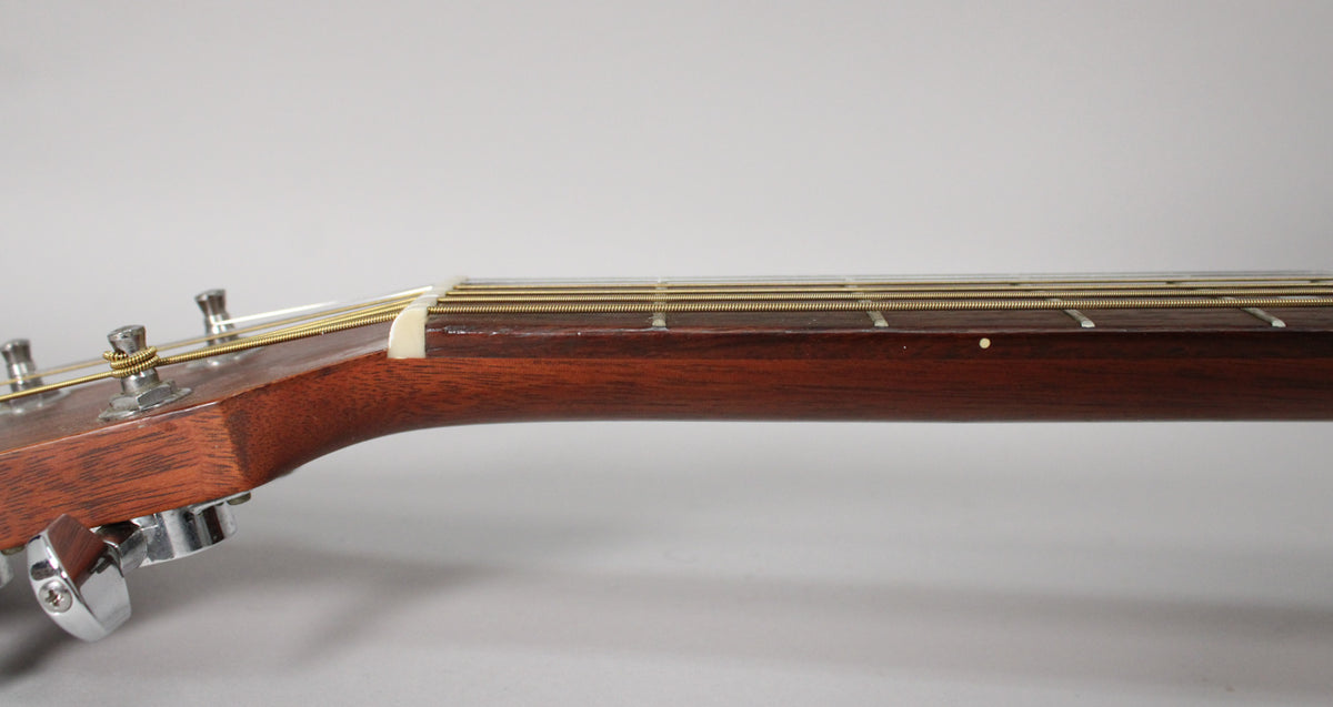 Close-up of the guitar's dark mahogany neck and headstock, showing chrome tuners, a white nut, and a single fret marker.