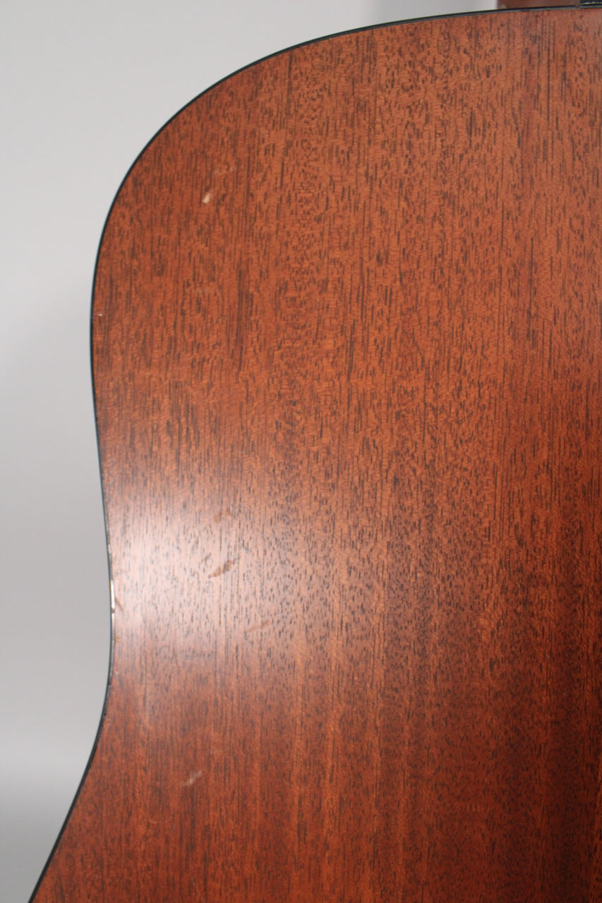 Close-up of the guitar's satin mahogany back, showing light scratches and dings on the lower bout and upper curve.