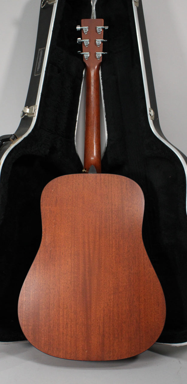 The guitar's mahogany back and neck are visible from behind, with six chrome tuners and a black hard shell case.