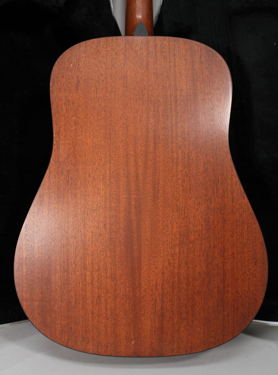 Full rear view of a reddish-brown mahogany acoustic guitar with a satin finish, showing minor scuffs and a dark neck heel.