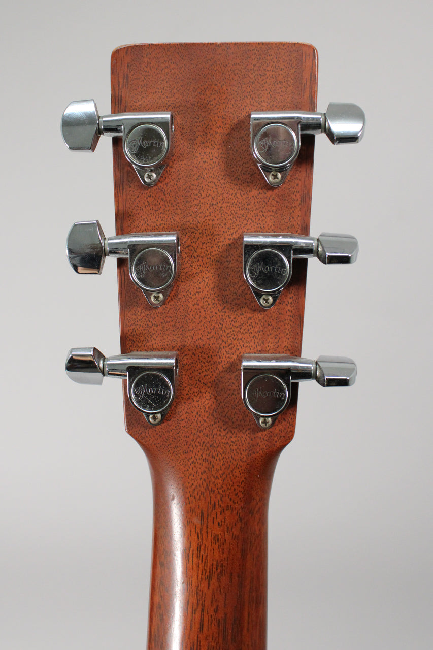 The guitar's mahogany headstock and neck are viewed from behind, showing six chrome tuners with light wear.