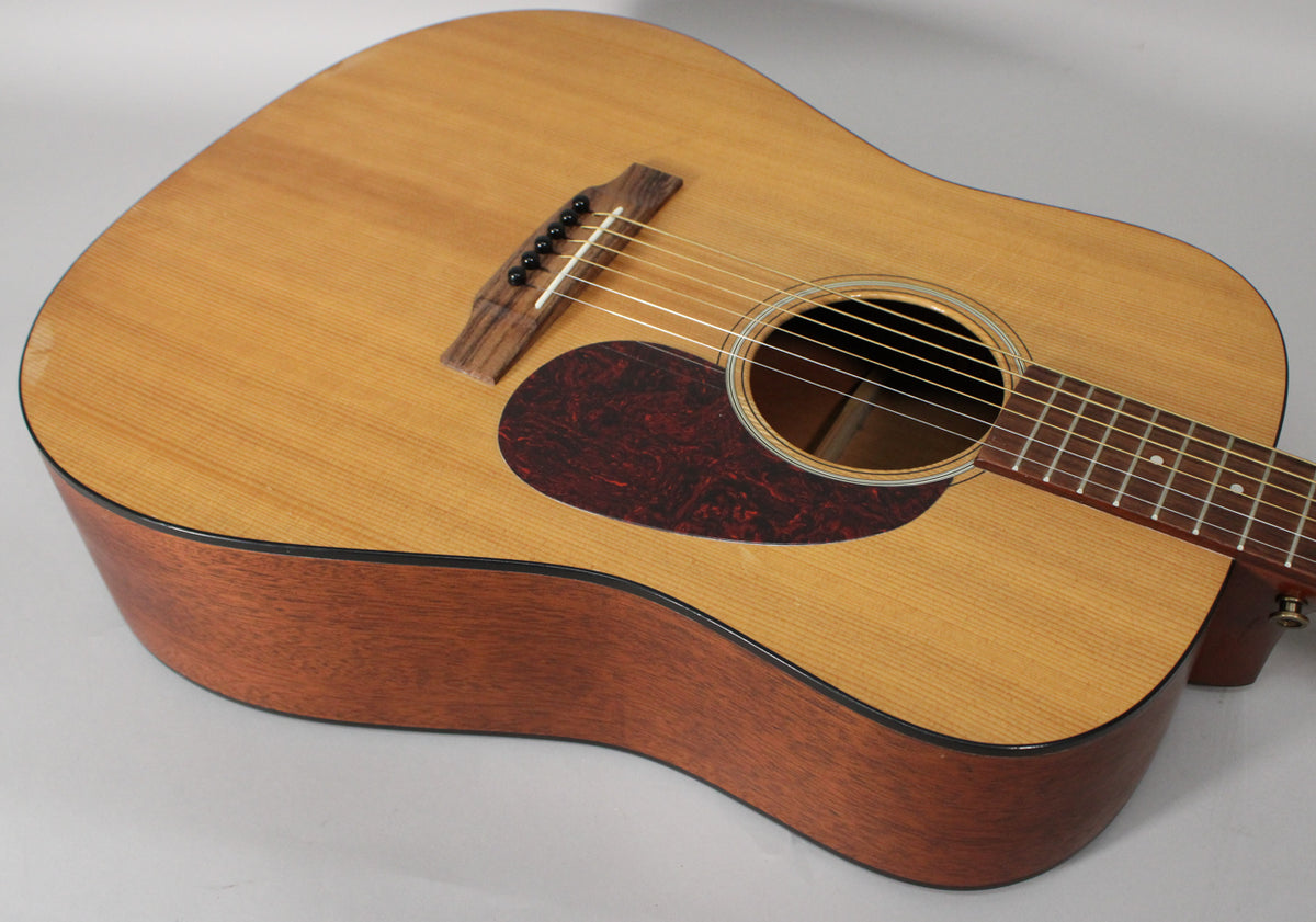 Close-up of the guitar's body, showing the light wood top, dark mahogany sides, tortoise pickguard, and rosewood bridge.