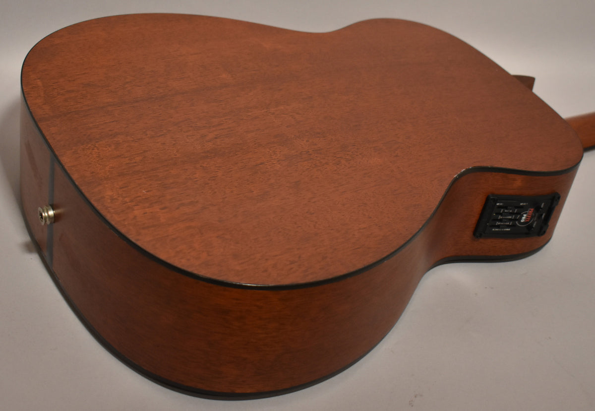 The guitar's back and side are visible, showing a matte reddish-brown finish, with an output jack and preamp controls on the side.