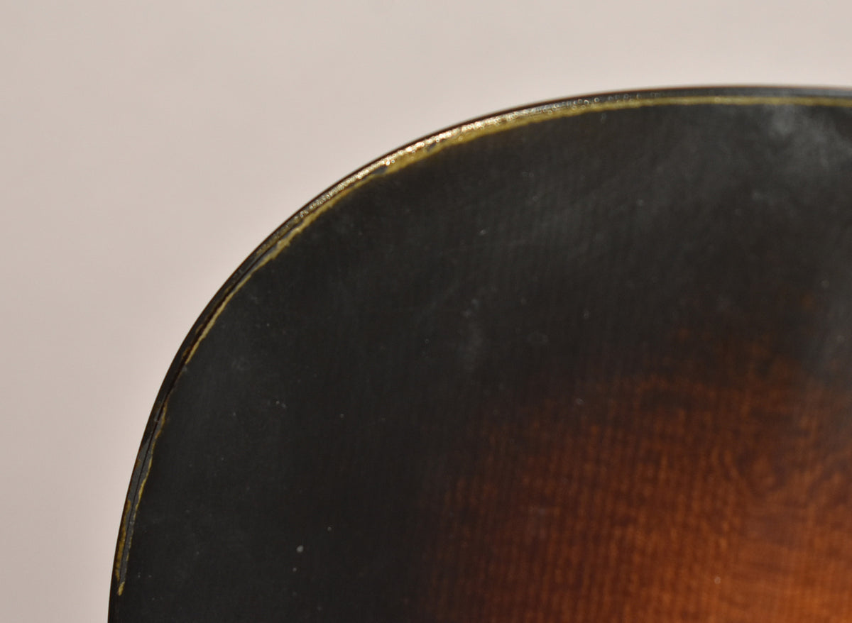 Close-up of the guitar's upper bout, showing the dark sunburst finish fading to brown, with light wear along the binding.