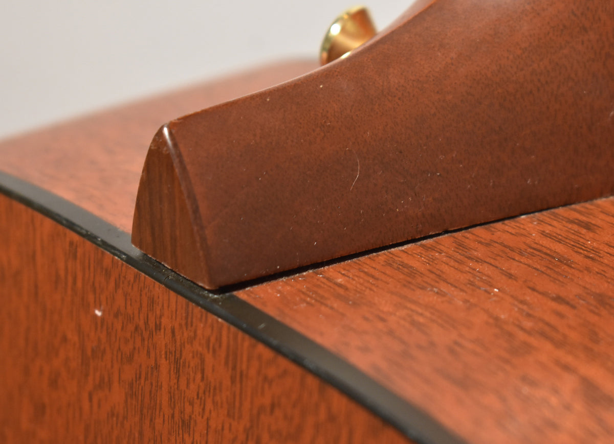 Close-up of the guitar's mahogany neck heel and body binding, showing a few small white flecks and light surface dust.