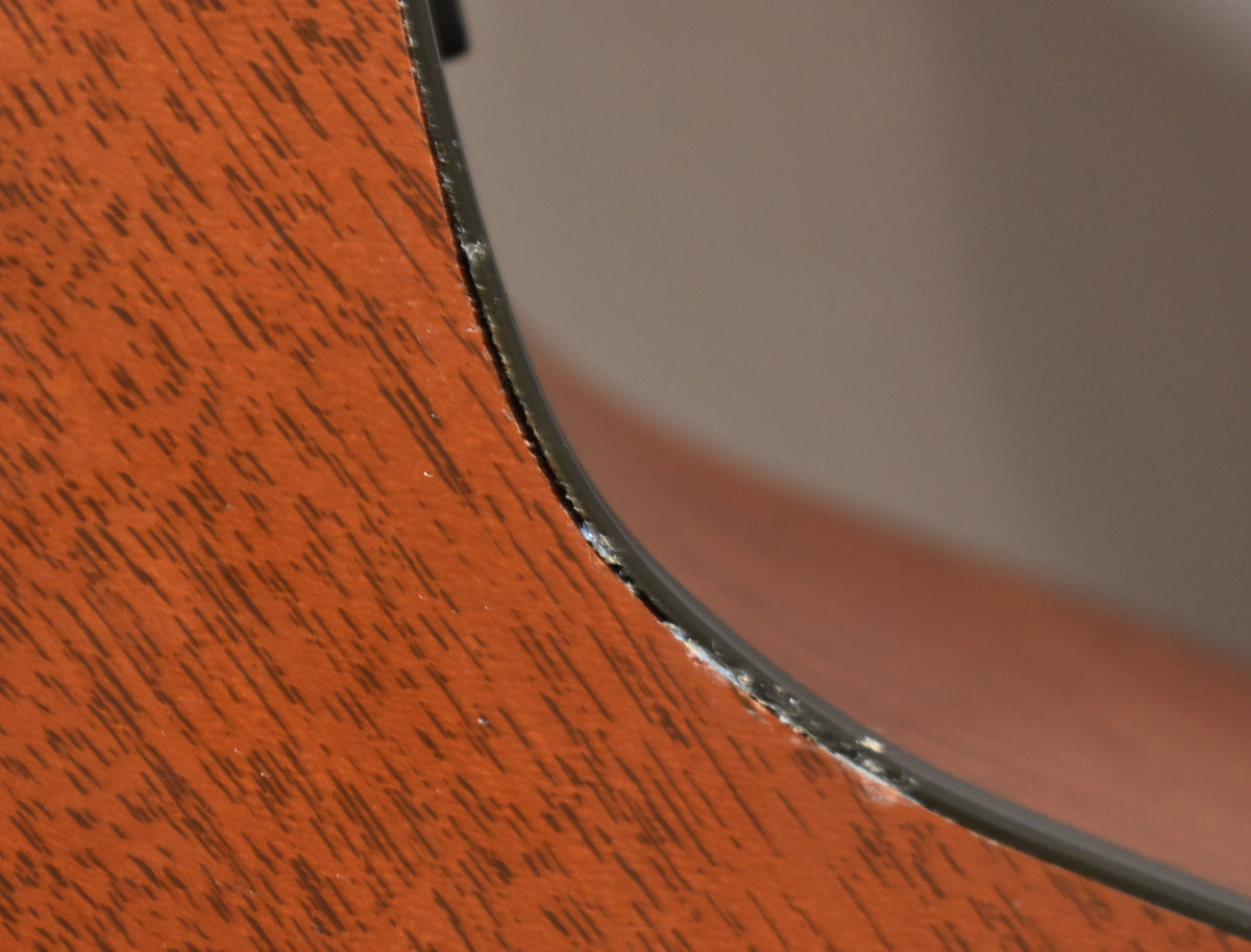 Close-up of the guitar's lower bout, showing a chipped binding and wear along the edge of the reddish-brown wood grain.