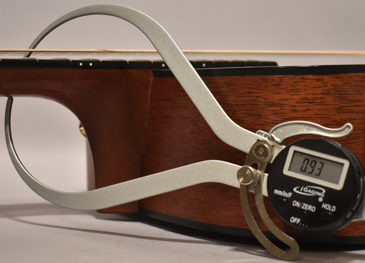 A digital caliper measures the guitar's action at the 12th fret, showing a reading of 0.93 inches.