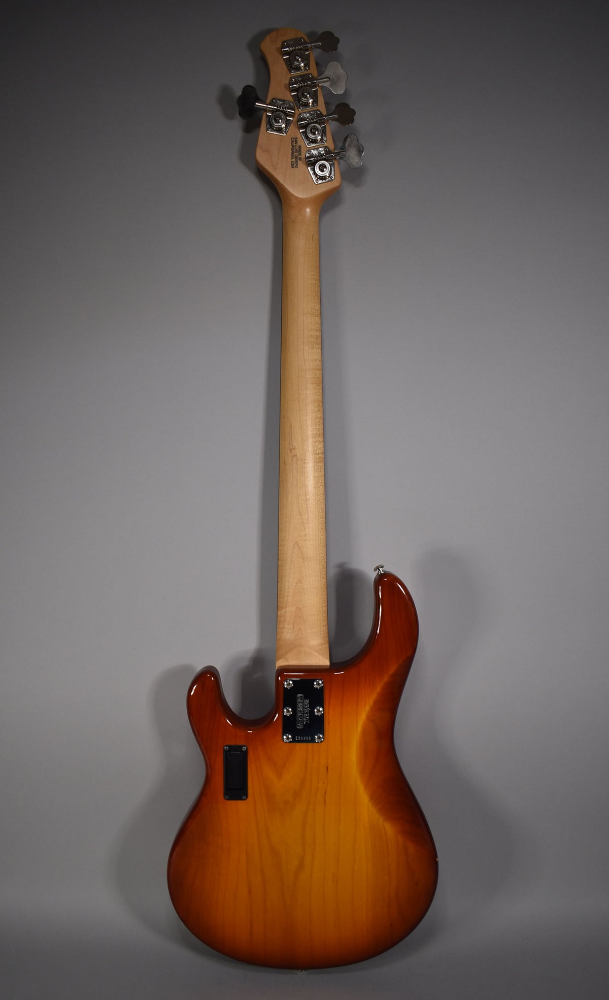 Full rear view of a 5-string bass with a honey sunburst finish, light maple neck, and chrome tuners on the headstock.